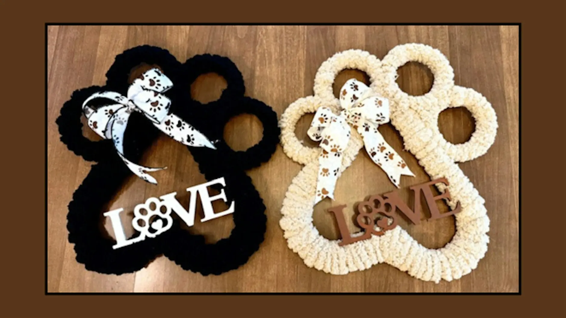 Two interlocking rings (one black, one cream) with paw-print ribbon bows and a 'LOVE' sign next to them on a wooden surface.